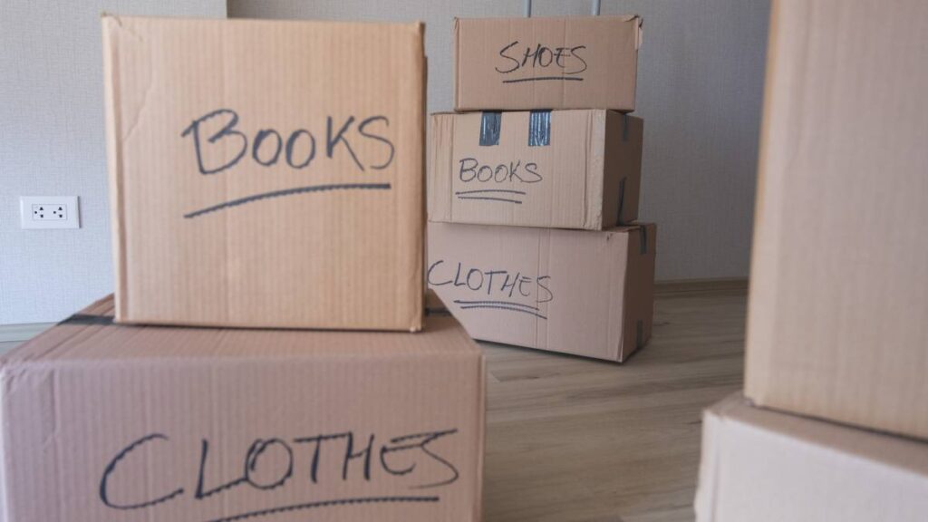 Cardboard moving boxes labeled 'Books,' 'Clothes,' and 'Shoes.' - where to get moving boxes