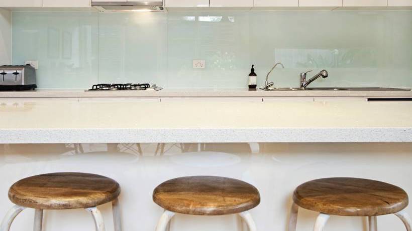 A contemporary kitchen featuring a smooth glass splashback that reflects light and provides a clean backdrop. - kitchen splashback types